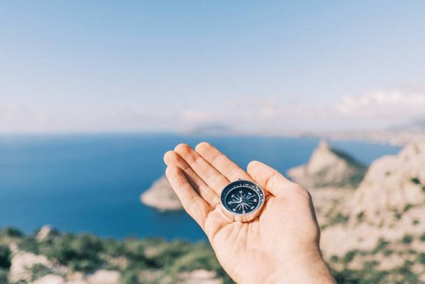 Man holding a compass in the background sea and mountains. - Foto, Imagem
