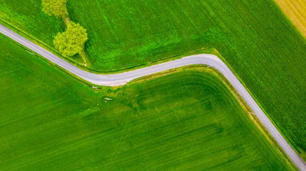Vista aérea del colorido paisaje con carretera en hermosos prados verdes en primavera. Vista superior desde arriba con dron, Viajes - Foto, Imagen