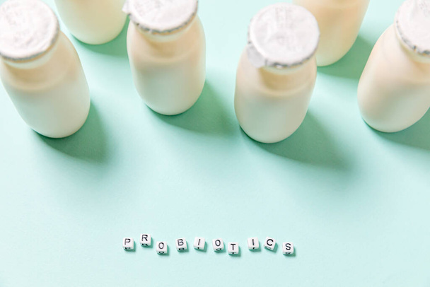 Mavi arka planda probiyotik ve prebiyotik süt ürünleri içeren küçük şişeler. Biyolojik olarak aktif katkı maddeleri üretimi. Fermantasyon ve diyet sağlıklı yiyecekler. Kullanışlı mikroorganizmalı biyo-yoğurt. - Fotoğraf, Görsel