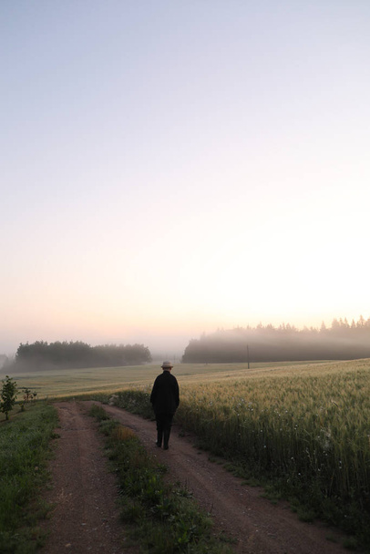 Silhouette eines Mannes, der bei Sonnenaufgang in einer malerischen Landschaft wandelt - Foto, Bild