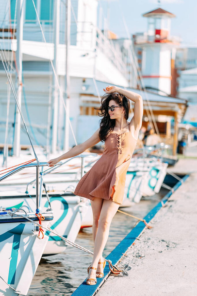 young beautiful healthy woman walks along the pier against the background of the yacht pier. Sea port in summer. A weekend trip. - Foto, Imagen