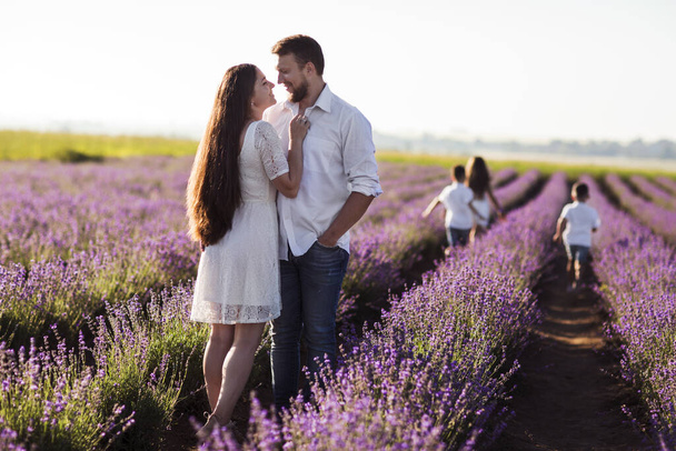 Piękna młoda rodzina na fioletowym polu lawendy kwiat. Rodzinne wakacje. Wesoła młoda para bawiąca się razem na polu lawendy. pole lawendy - Zdjęcie, obraz