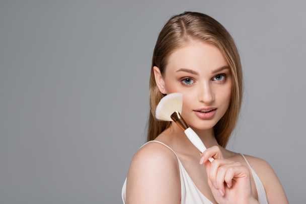 pretty woman holding cosmetic brush isolated on grey - Foto, Imagem