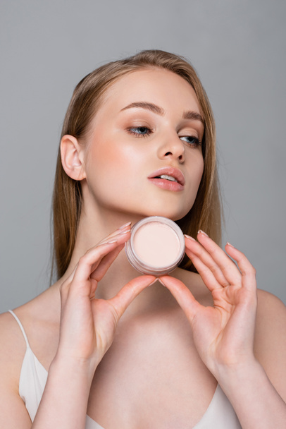 pretty young woman holding face powder container isolated on grey - Photo, Image