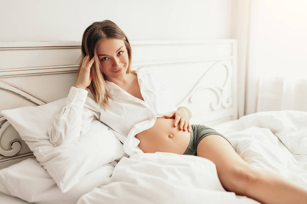 Happy pregnant woman resting on bed - Zdjęcie, obraz