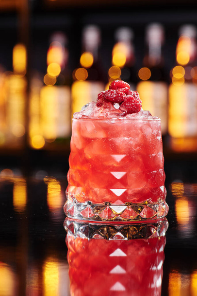 Beautiful red cocktail in an elegant glass on a bar counter in a nightclub, close-up. Space for text. - Photo, Image