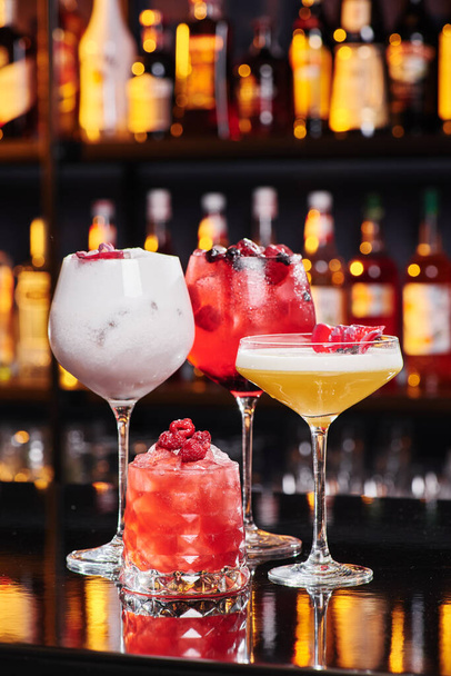 Four different fruit cocktails in beautiful glasses on the bar in a nightclub. Space for text. - 写真・画像