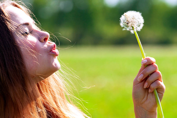 Woman blowing on a dandelion - Photo, Image