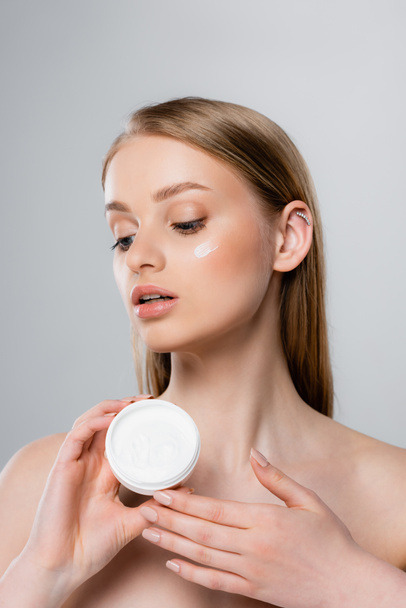 pretty woman with blue eyes holding container with face cream isolated on grey - Photo, Image