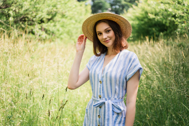 Woman in striped dress holding straw hat in park  - Photo, Image