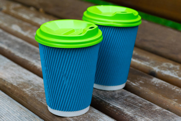 Paper coffee cups in the park on a bench. Concept of coffee to go, communication and relaxation - Foto, Imagen