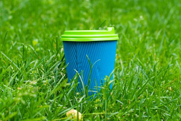 Kubek papierowy z kakao, kawą lub herbatą na zielonym trawniku w parku latem lub wiosną - Zdjęcie, obraz