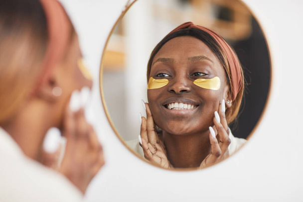 Νεαρή Αφρο-Αμερικανίδα να χαμογελάει στον καθρέφτη - Φωτογραφία, εικόνα