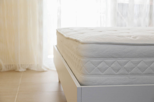 White orthopedic mattress top side surface pattern on unmade bed in the bedroom. Hypoallergenic foam mattress for proper spinal alignment and pressure point relief. Background, copy space, close up. - 写真・画像