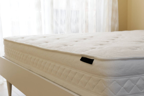 White orthopedic mattress top side surface pattern on unmade bed in the bedroom. Hypoallergenic foam mattress for proper spinal alignment and pressure point relief. Background, copy space, close up. - Фото, изображение