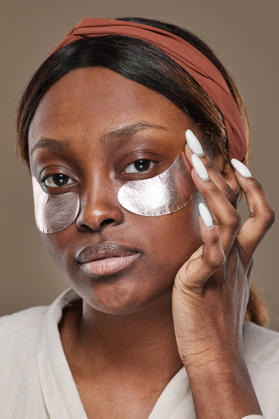Mooie Afrikaanse Amerikaanse vrouw met behulp van moisturizer patches - Foto, afbeelding