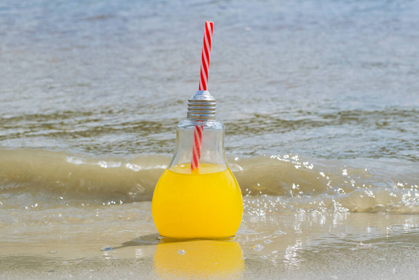 Φρέσκο, λεμονάδα ή cocktail σε γυάλινο μπουκάλι με καλαμάκι κοντά στην άμμο της παραλίας κοντά στο νερό. Έννοια ταξιδιού και αναψυχής. - Φωτογραφία, εικόνα
