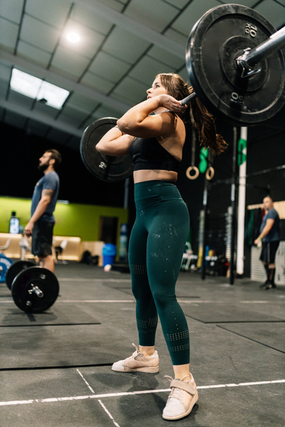 Mujer realizando un ejercicio de levantamiento de pesas dentro de un gimnasio - Foto, imagen