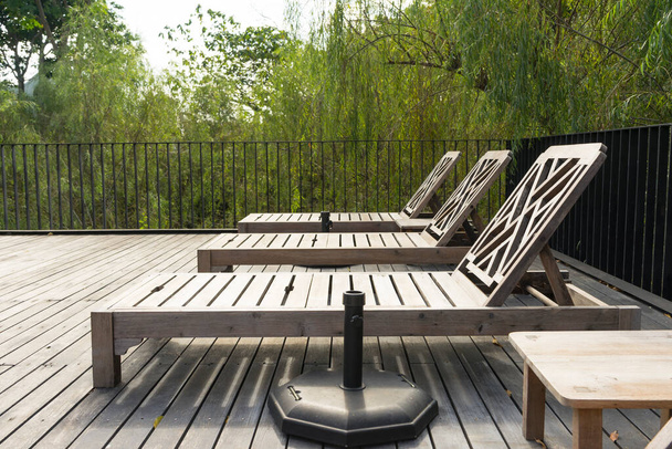 Chaises longues en bois sur terrasse avec piscine. - Photo, image