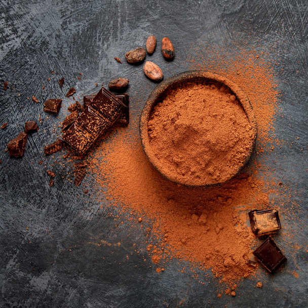 Cacao beans and chocolate on gray background. Superfood concept. Top view, flat lay, copy space - Fotografie, Obrázek