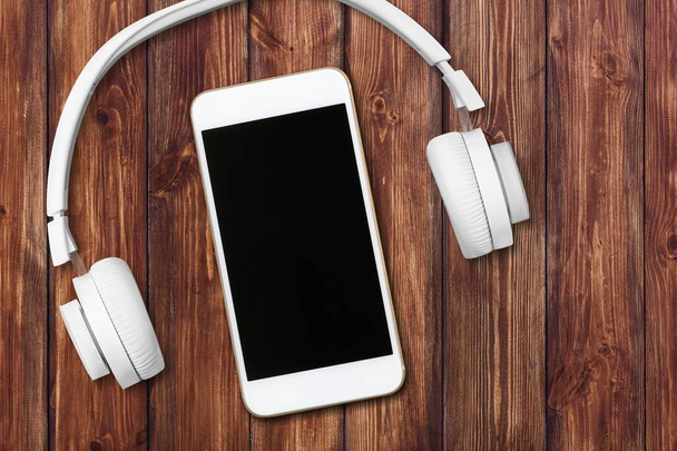 Koncept hudebního přehrávače s prázdnou obrazovkou mobilního telefonu a sluchátek na dřevěném povrchu - Fotografie, Obrázek