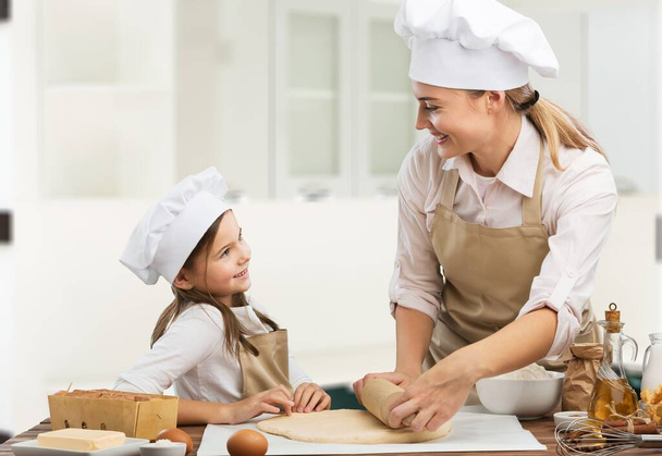 Cheerful happy mom teaching daughter how to prepare food - Photo, image