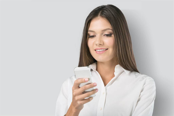 Pretty young woman using smartphone standing on the background. - Foto, Imagen