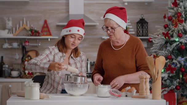 Senior woman teaching grandchild who to straing flour ingredient in bowl - Footage, Video