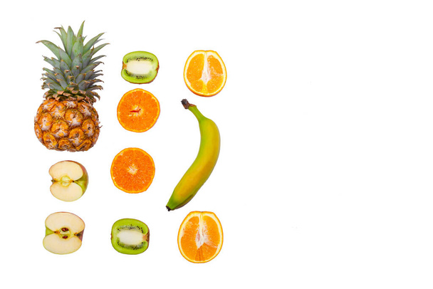 Creative mockup of oranges, kiwi, pineapple, banana, apples and tangerines on a white isolated background. Healthy eating. View from above. - Photo, Image