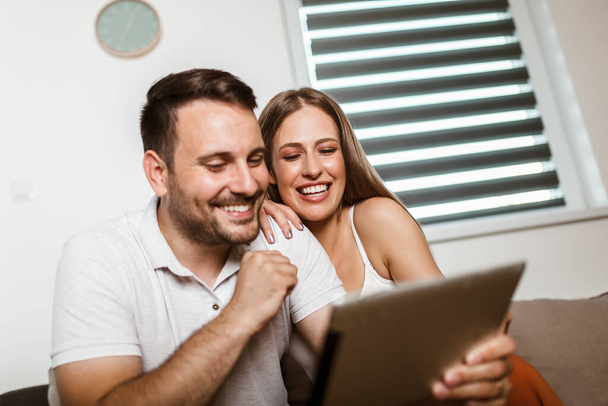 Joyeux jeune couple faisant des achats en ligne avec tablette - Photo, image