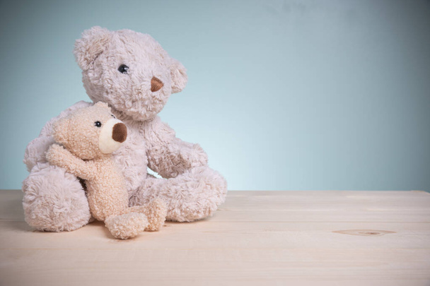 Grote en kleine bruine teddyberen zitten knuffelig show liefde, geluk op een oude houten tafel met kopieerruimte. Concept familie, liefde, en Valentijnsdag festival. - Foto, afbeelding