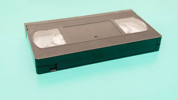Vista próxima de uma fita VHS antiga sobre uma superfície de ciano - Foto, Imagem