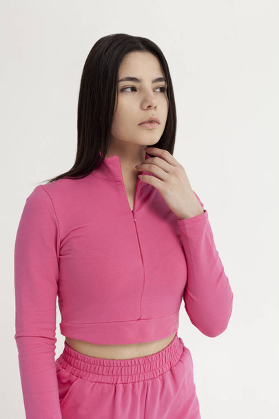 beautiful brunette in a pink tracksuit on a light background - Photo, Image