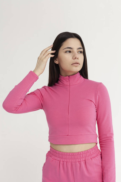 beautiful brunette in a pink tracksuit on a light background - Foto, afbeelding