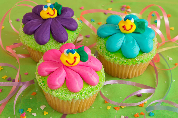 Cupcake kohtelee leivotaan kukkia ja hauskaa hymiö kasvot edistää strösseleitä ja serpentiinit - Valokuva, kuva