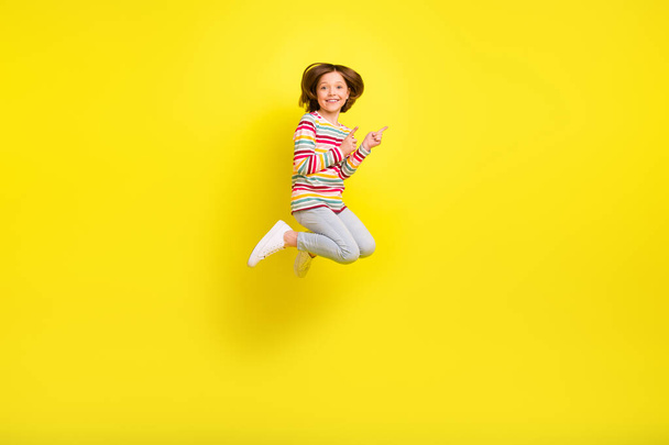 Full body photo of charming cheerful young small girl jump up point finger empty space isolated on yellow color background - Photo, image