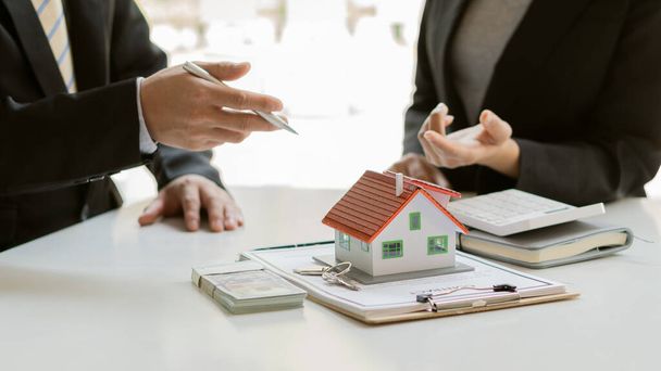 Satış temsilcisi ev veya daire satın almak için bir ev satın alma sözleşmesi sunar ve müşteriye gayrimenkul alım veya satım ofisinde bir ev anahtarı verir.. - Fotoğraf, Görsel