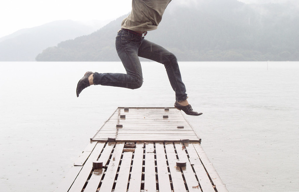 Hombre saltando en un muelle de madera
 - Foto, imagen