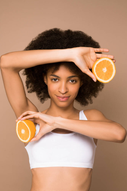 Egy fiatal, göndör hajú mulatta narancsszeletekkel. - Fotó, kép