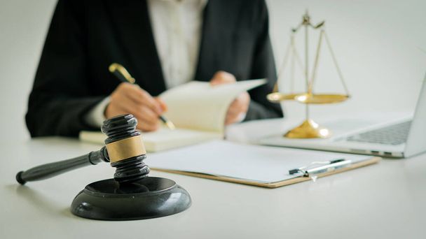 Lawyers discuss contract paperwork with brass scales on tables and hammers in the office. Legal advisory services. Advice. Justice. - Photo, Image