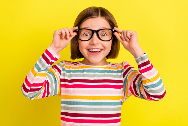 Photo portrait little girl amazed wearing glasses smiling cheerful isolated vibrant yellow color background - Foto, Imagem