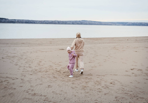 Mom and daughter play summer on the beach sunset - Фото, изображение