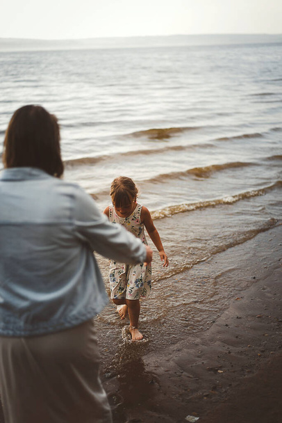 Mom and daughter play summer on the beach sunset - Foto, Imagen