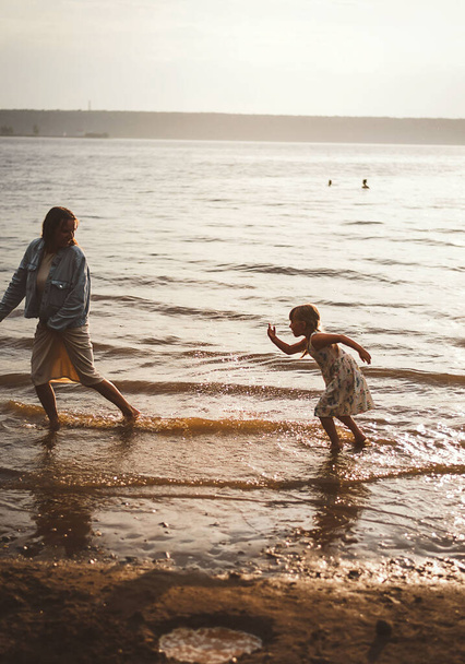 Mom and daughter play summer on the beach sunset - Photo, Image