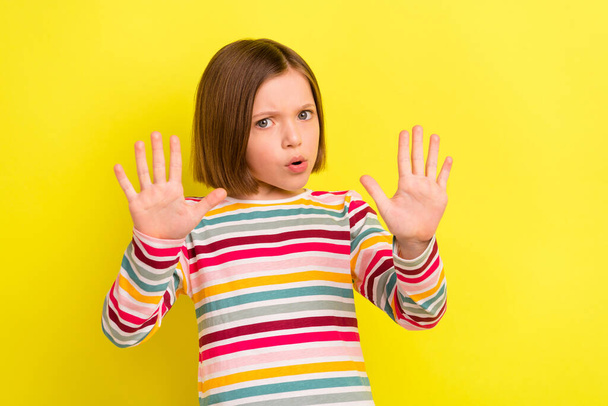 Foto de una joven infeliz niña cogida de la mano señal de stop rechazar negativo aislado en el fondo de color amarillo - Foto, Imagen