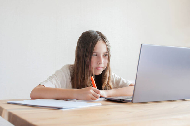 Küçük bir kız evdeki bir bilgisayarda kitap ve defterlerle çalışıyor. Çevrimiçi eğitim, uzaktan öğrenme, karantina. Kavram  - Fotoğraf, Görsel
