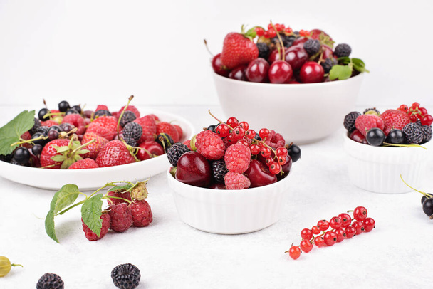 Plates with various berries on a white background, summer harvest, close-up. - Фото, изображение
