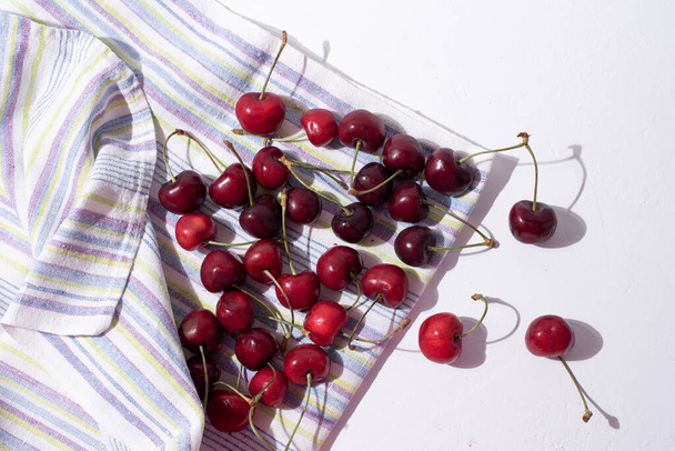 Harvest of summer berries, washed fresh cherries on a kitchen towel on a white background, close-up. - Foto, Bild