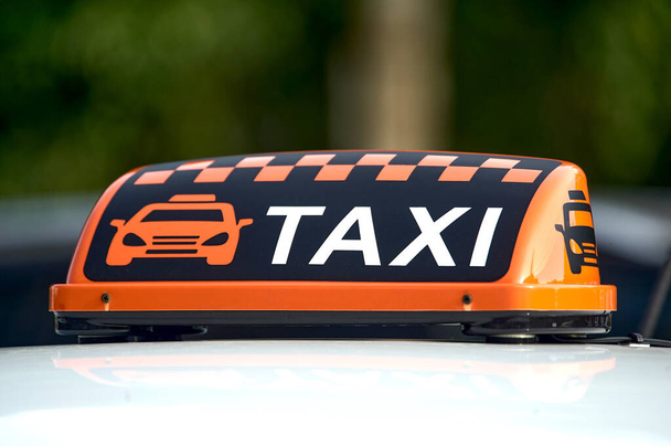 un cartello arancione taxi si erge sul tetto della macchina - Foto, immagini
