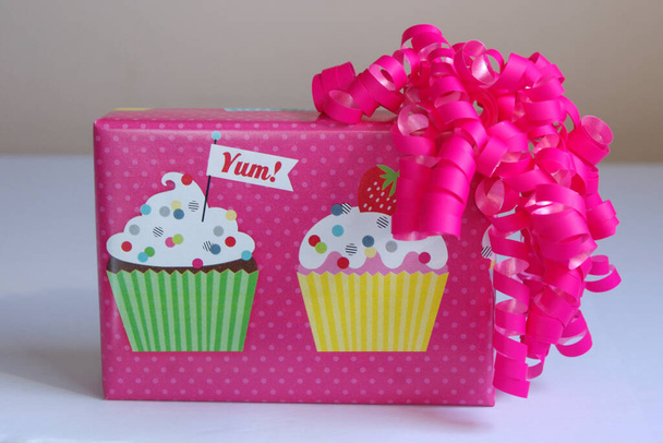 рожевий кекс на день народження загорнута коробка з яскраво-рожевим бантом
  - Фото, зображення